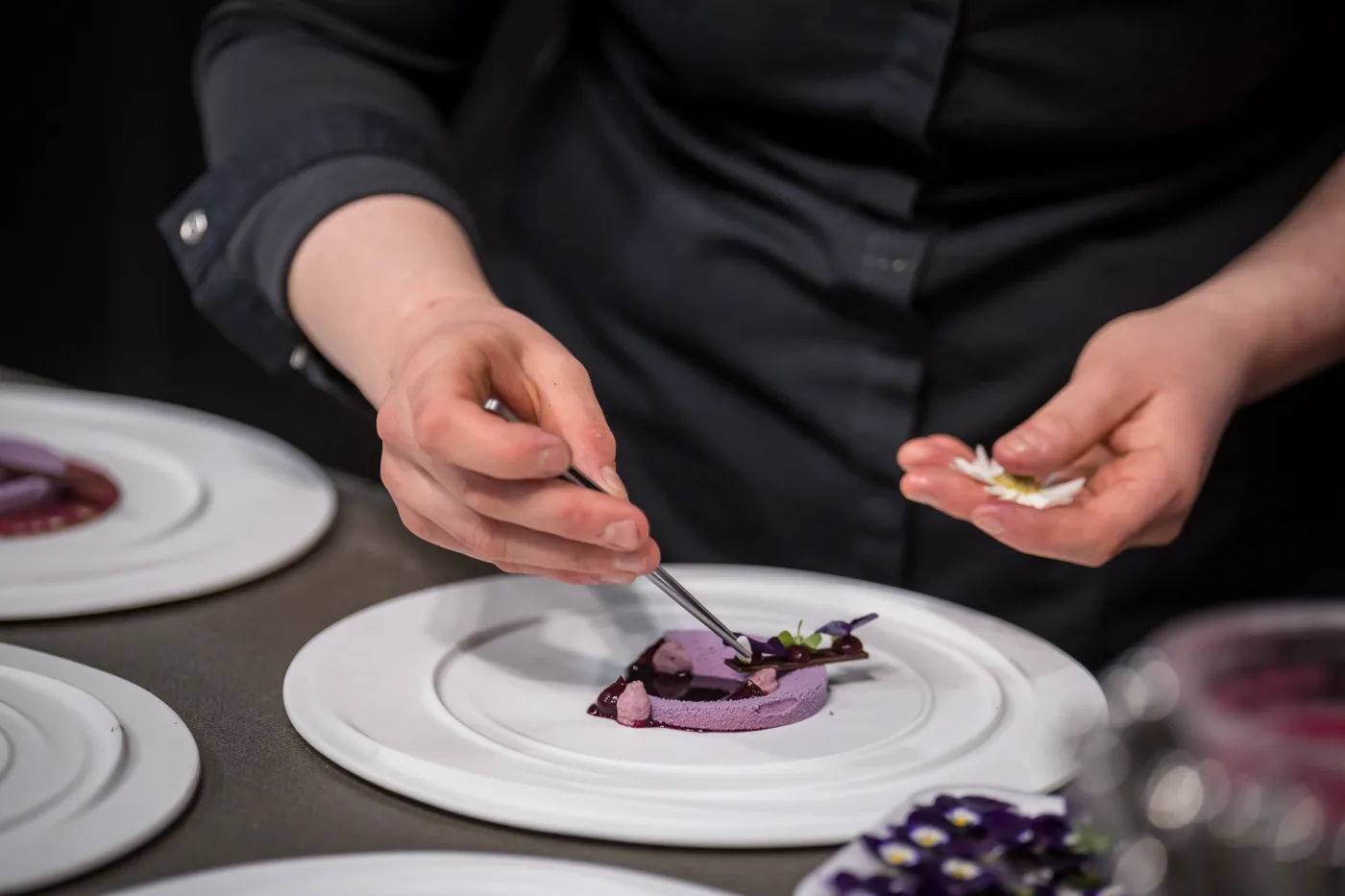 Köchin richtet ein Dessert mit der Pinzette an