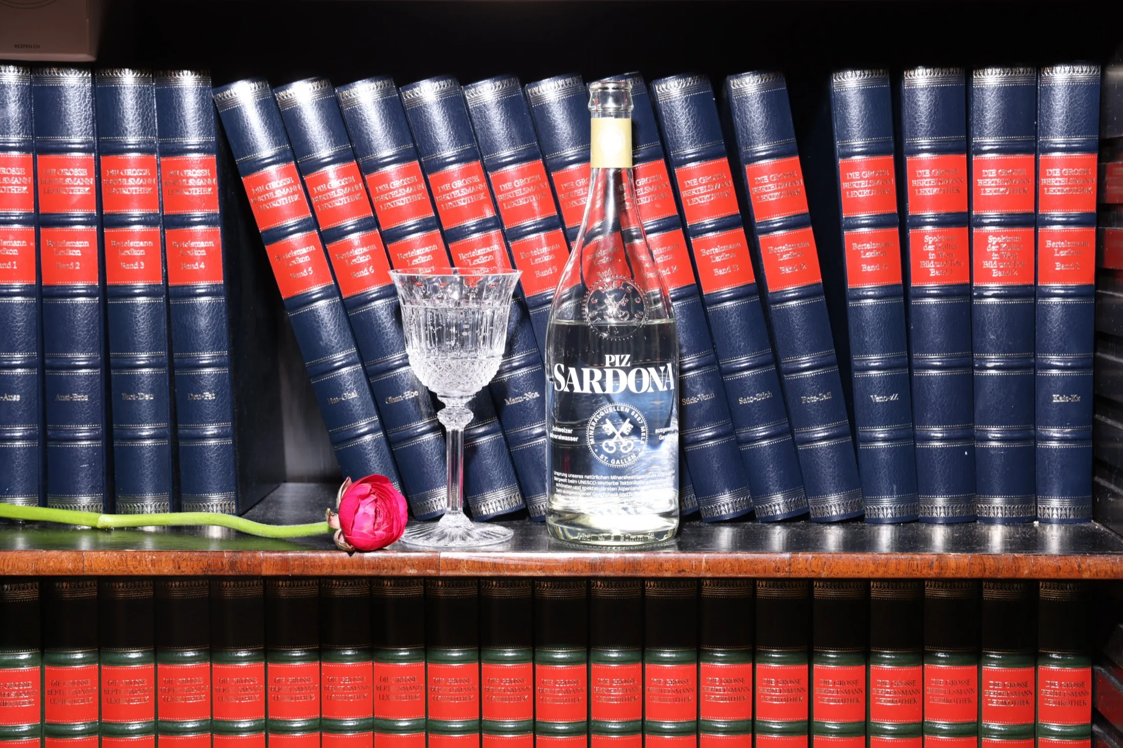 Piz Sardona Flasche mit Kristallglas vor einer Bücherwand